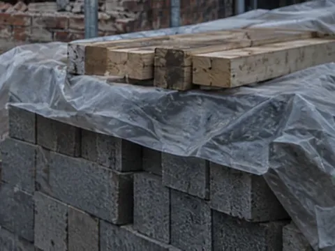 Blocks and timber stacked on site under sheeting